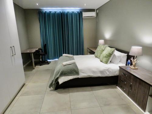 a bedroom with a bed and a desk and a window at The Executive - Exclusive Self-Catering Apartments - Ezulwini in Ezulwini