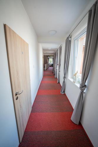 a long corridor with a red carpet and open doors at Penzion Zuzana in Staré Splavy
