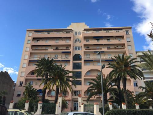 a tall building with palm trees in front of it at Amazing View Port Golfe-Juan and Garage in Golfe-Juan