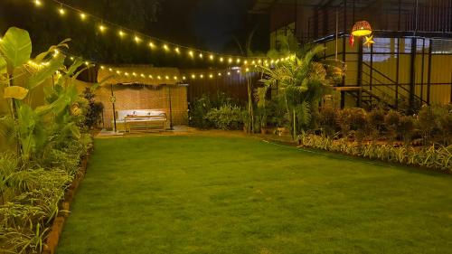 un giardino di notte con luci e un prato di Vayu Villa By The Sea a Canacona