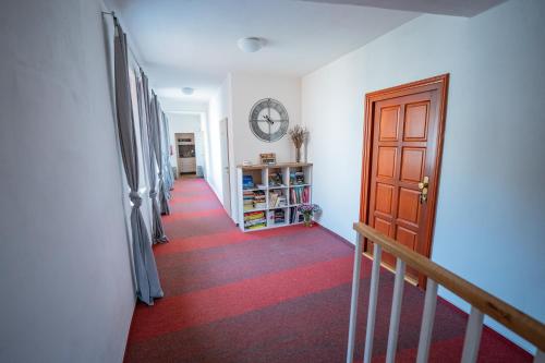 a hallway with a red carpet and a wooden door at Penzion Zuzana in Staré Splavy