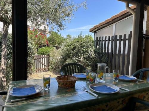 une table verte avec des assiettes et des verres sur une terrasse dans l'établissement SP320-519 Maison 2 pièces mezzanine SAINT PIERRE LA MER, à Saint Pierre La Mer
