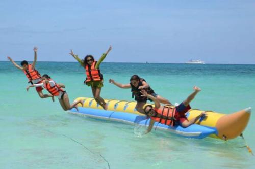 a group of people jumping off a raft in the water at Tarkarli beach guest house in Bhogwe