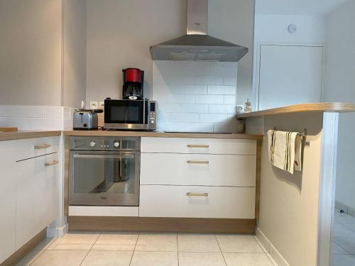 une cuisine avec une cuisinière et un micro-ondes dans l'établissement Appartement 2 chambres avec terrasse au cœur de Perros-Guirec, parking inclus - FR-1-368-449, à Perros-Guirec