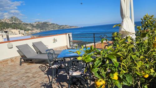 taras ze stołem i krzesłami i widokiem na ocean w obiekcie Panoramic Terrace Room w mieście Giardini Naxos