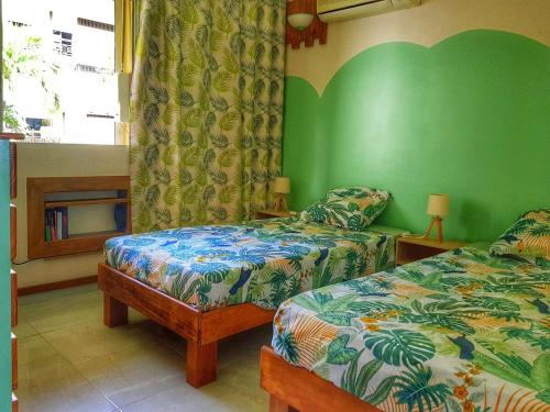 1 Schlafzimmer mit 2 Betten und einer grünen Wand in der Unterkunft Appartement de la mer in Le Gosier
