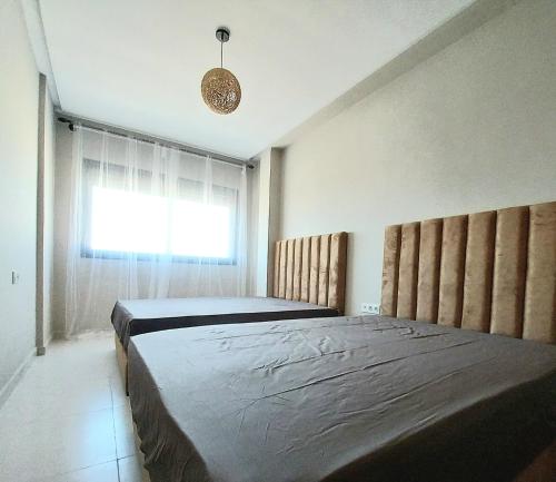 a bedroom with two beds and a window at Family airport relax apartment in Deroua