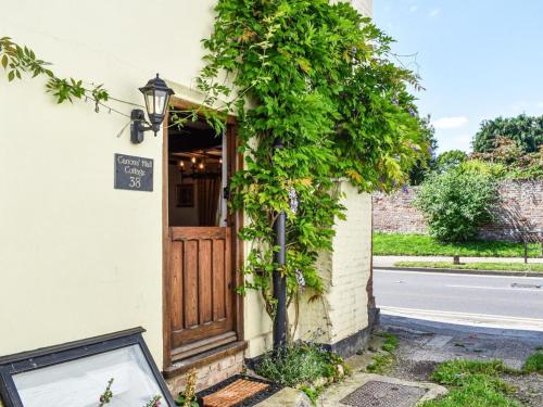 a building with a wooden door and ivy at Historic Tudor Cottage, free parking, sleeps 6 and dog friendly! in Wingham