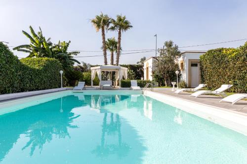 una piscina con sillas y palmeras en Villa del Sole - Salento Mille e una Notte, en Torre Suda