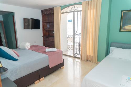 a bedroom with two beds and a balcony at Hotel Galería La Vieja Sara in Ríohacha