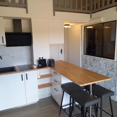 une cuisine avec une table en bois et deux tabourets dans l'établissement Appartement Cap d'Agde 
