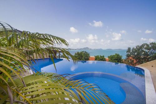 a blue swimming pool with a view of the ocean at Boujis Boutique Resort in Chaweng Noi Beach