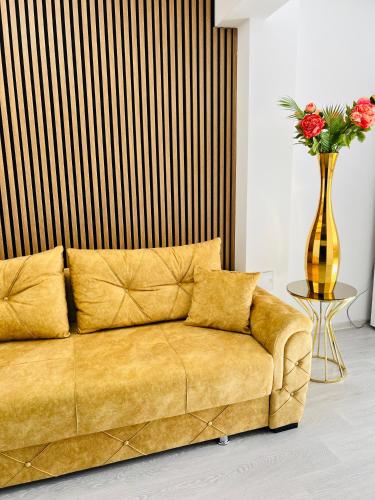 a yellow couch in a room with a vase of flowers at Gold House in Bucharest