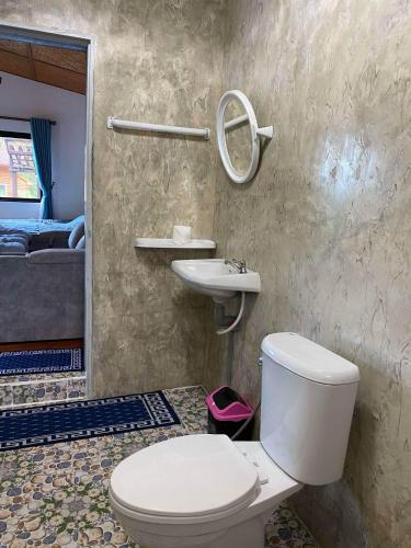 a bathroom with a toilet and a sink and a bed at บ้านมานอนดอย - Manondoi โฮมสเตย์เชียงดาว in Ban Pang Klang