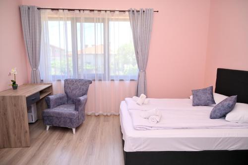 a bedroom with two beds and a chair and a desk at КЪЩА ЗА ГОСТИ ГРОШЪ in Dobrinishte