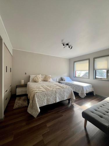 Un dormitorio blanco con dos camas y un sofá. en Departamento Álamo, en Puerto Montt