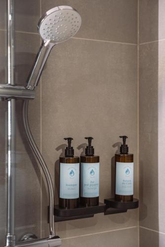 a shelf with three soap bottles on it in a bathroom at Termy Karkonosze Resort & Spa koło Karpacza in Staniszów