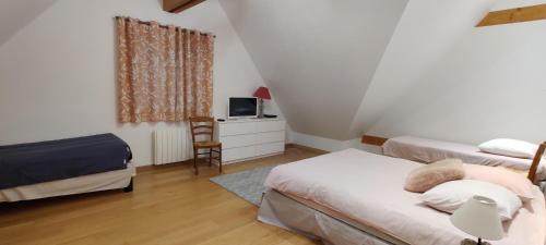 a bedroom with two beds and a tv and a chair at Camping la Haie Penée **** in Saint-Quentin-en-Tourmont