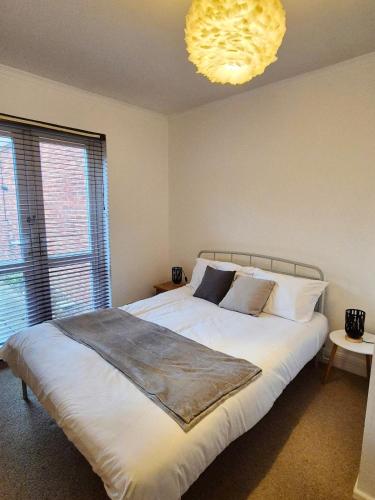 a bedroom with a large white bed and a chandelier at Ground floor apartment close to the train station and town centre - By ShireStays in Bicester