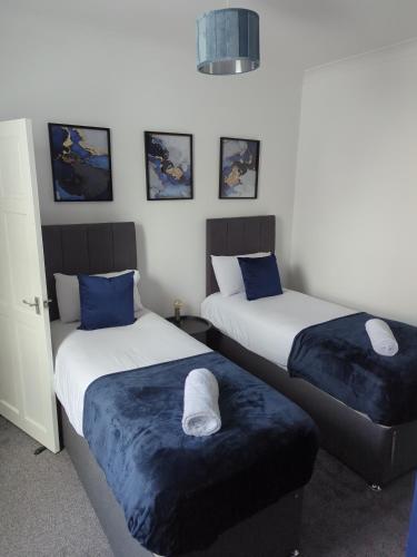 a bedroom with two beds with blue pillows at Charming 3-Bedroom House - Prime Location in Wolverhampton! in Wolverhampton