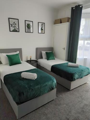 two beds sitting next to each other in a bedroom at Charming 3-Bedroom House - Prime Location in Wolverhampton! in Wolverhampton