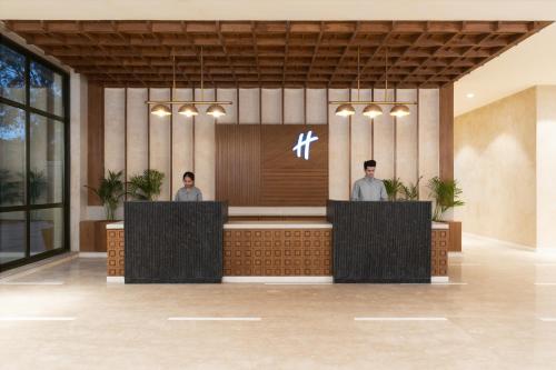 a rendering of a lobby with two men standing at the counter at Holiday Inn Gurgaon NH8 by IHG in Gurgaon