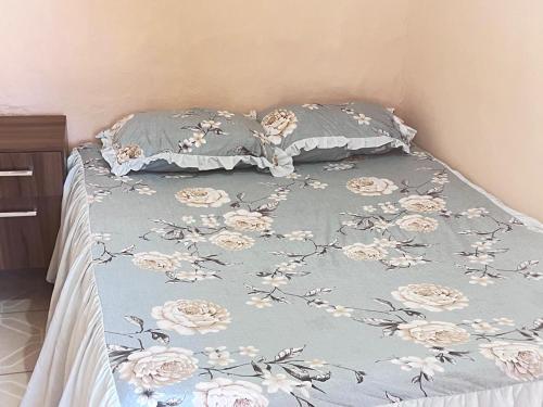 a bed with a blue blanket with flowers on it at Pousada Brisa do Mar in Tramandaí