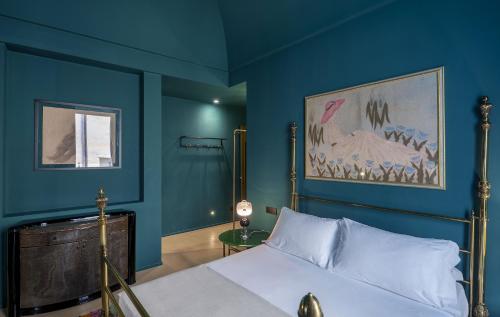a bedroom with blue walls and a bed with white sheets at Fiermonte Museum by La Fiermontina in Lecce
