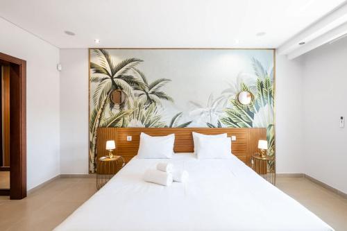 a bedroom with a large white bed with a mural of palm trees at Villa Adaro - Large Luxury close to marina in Albufeira