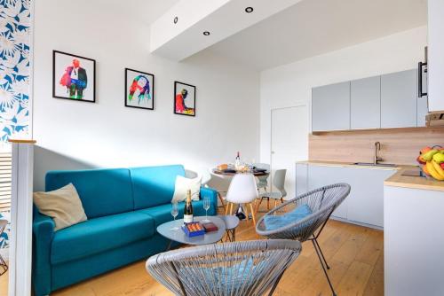 un salon avec un canapé bleu, une table et des chaises dans l'établissement Bluestay 48 - Superb apartment in Paris, à Paris