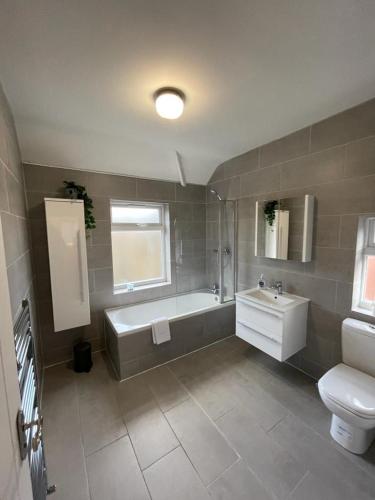 a bathroom with a tub and a toilet and a sink at Harborne Park House in Birmingham