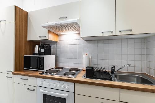 eine weiße Küche mit Spüle und Mikrowelle in der Unterkunft Spacious 3-room apt. 15 min to the city center in Wien