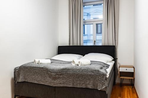 ein Bett mit zwei Kissen und einem Fenster in der Unterkunft Spacious 3-room apt. 15 min to the city center in Wien