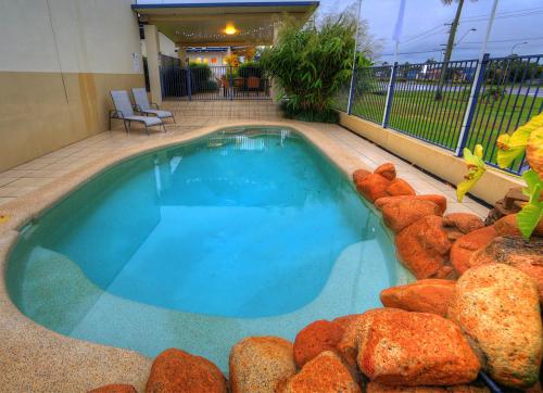 a swimming pool with blue water in a building at Tropixx Motel in Ingham
