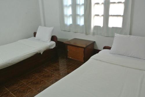 een kleine kamer met twee bedden en een raam bij Syvongsack Guesthouse in Pakbeng