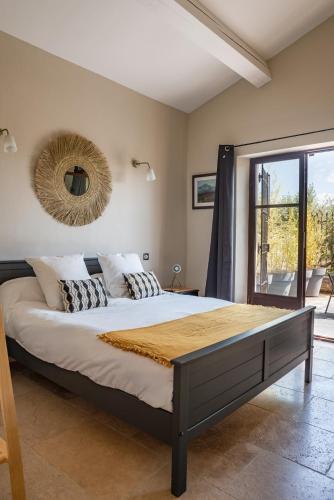 une chambre avec un grand lit avec un miroir au mur dans l'établissement Bastide Aubignan, à Aubignan