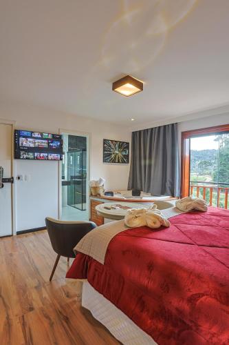 a bedroom with a red bed and a bathroom at La Vita Pousada de Charme in Campos do Jordão