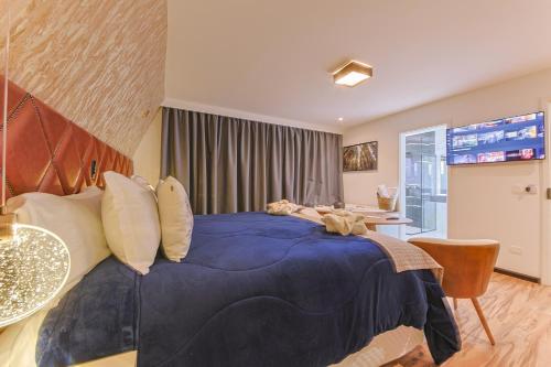 a bedroom with a large bed with a blue blanket at La Vita Pousada de Charme in Campos do Jordão
