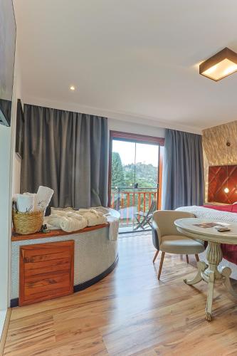 a living room with a bed and a table and a dining room at La Vita Pousada de Charme in Campos do Jordão