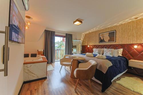 a hotel room with a bed and a table and chairs at La Vita Pousada de Charme in Campos do Jordão