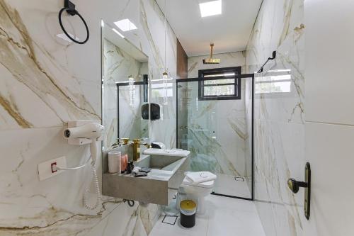a bathroom with a sink and a toilet and a shower at La Vita Pousada de Charme in Campos do Jordão