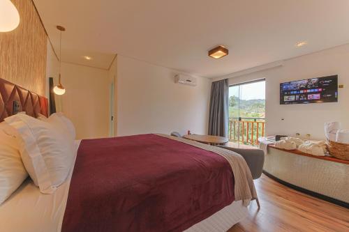 a bedroom with a large bed and a balcony at La Vita Pousada de Charme in Campos do Jordão
