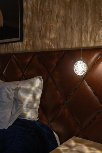 a bed with a brown head board with a light at La Vita Pousada de Charme in Campos do Jordão