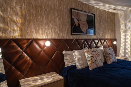 a bedroom with a blue bed with a brown headboard at La Vita Pousada de Charme in Campos do Jordão