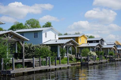 a row of houses next to a body of water at Waterresort Bodelaeke Giethoorn in Giethoorn