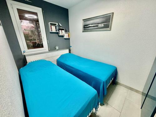 une chambre d'hôpital avec deux lits bleus et une fenêtre dans l'établissement Appartement climatisé à 700m de la plage avec garage - FR-1-816-20, à Bormes-les-Mimosas