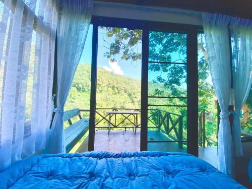 a bedroom with a bed and a window with a view at บ้านมานอนดอย - Manondoi โฮมสเตย์เชียงดาว in Ban Pang Klang