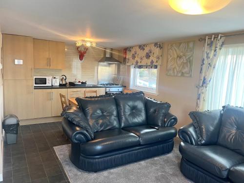 a living room with two leather couches and a kitchen at Red Deer Village Holiday Park - 3 Bedroom, Self-Catering Chalet in Steps