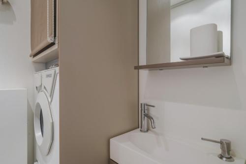 une salle de bain avec un lavabo et une machine à laver dans l'établissement Paris Marais Bouquet Residence, à Paris