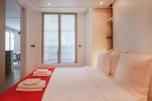 une chambre avec un grand lit blanc avec des serviettes dessus dans l'établissement Paris Marais Bouquet Residence, à Paris